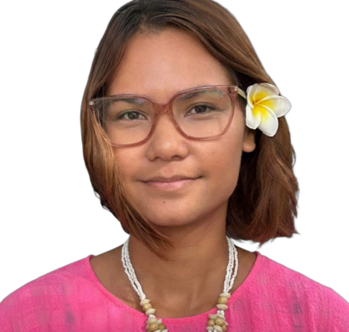 Woman wearing a pink blouse, pink-framed glasses, a white plumeria in her hair, and a large shell pendant necklace against a black background.
